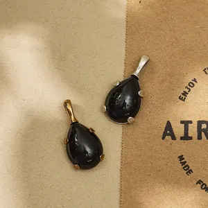 Detailed view of black teardrop gemstone pendants with gold and silver claw settings