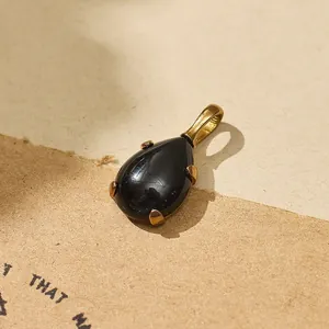 Detailed view of a black teardrop gemstone pendant in 18k gold plated titanium steel