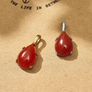 Detailed macro view of teardrop red gemstone pendants with gold and silver claw settings