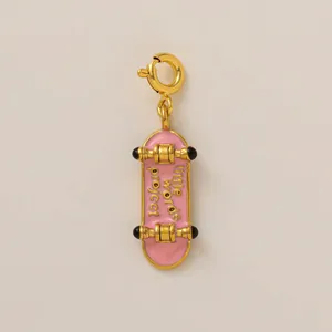 Gros plan d'un pendentif skateboard en émail rose avec placage à l'or 18 carats et texte.