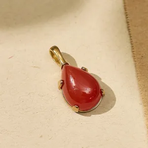 Macro view of teardrop red gemstone pendant with 18k gold-plated titanium steel frame