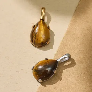 Detail view of teardrop tiger's eye pendants with gold and silver steel settings