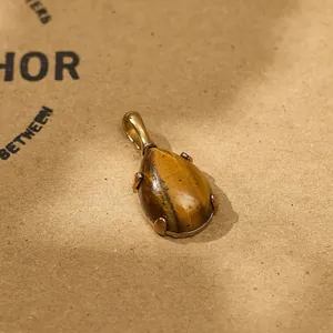Detailed macro shot of a tiger's eye teardrop pendant with gold-plated setting