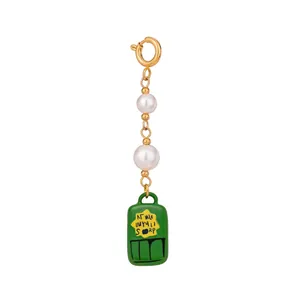 Dettaglio di catena dorata con perle e pendente in smalto verde per gioielli estivi.