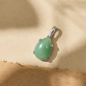 Macro detail of a green waterdrop gemstone pendant in a polished titanium steel setting.