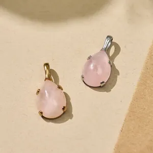 Close-up of teardrop rose quartz pendants with gold and silver steel settings