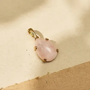 Detailed macro view of a rose quartz teardrop pendant in 18k gold-plated frame.