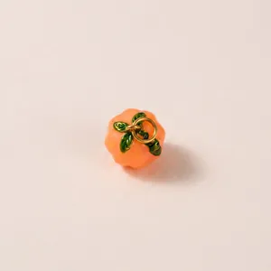Dettaglio di un piccolo ciondolo a forma di zucca arancione per gioielli fai da te.