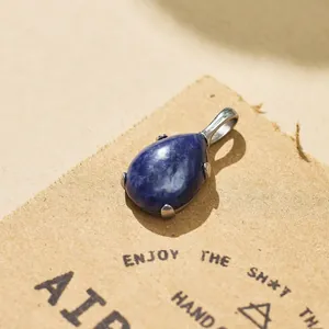 Close-up of teardrop blue stone pendant with silver titanium steel claw setting