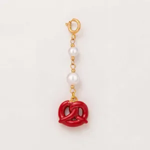 Dettaglio di un ciondolo a forma di pretzel rosso con perle e catena d'oro