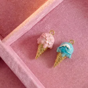 Dettaglio di ciondoli a forma di gelato smaltati con ciliegio e motivi a onde blu.