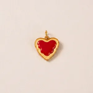 Primo piano di un ciondolo a cuore in smalto rosso con eleganti bordi dorati ondulati.