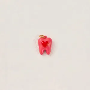 Dettaglio di un ciondolo rosa a forma di dente con cuore rosso per creazione gioielli