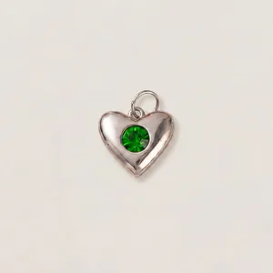 Dettaglio di un ciondolo a cuore in acciaio inossidabile con gemma verde brillante