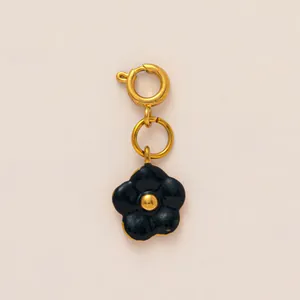 Close-up of black enamel flower charm with gold spring ring clasp for DIY jewelry