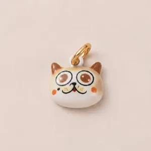 Gros plan d'un pendentif chat de dessin animé avec de grands yeux et un anneau doré.