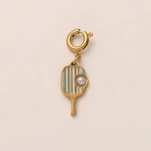 Détail d'un pendentif raquette de pickleball doré avec perle élégante sur fond neutre