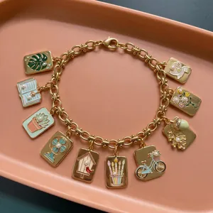 Detailed view of gold charm bracelet with monstera, succulent, and bicycle enamel pendants.