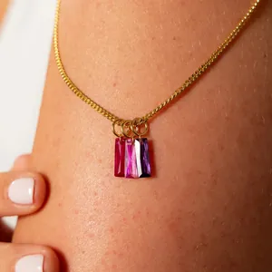 Close-up of gold stainless steel necklace with three purple and pink zircon birthstone charms.