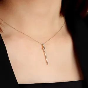 Dettaglio macro di una collana con ciondolo a frangia placcata oro con cristalli lucidi.