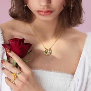 Elegant gold floral horseshoe necklace with pink blossoms and white crystals on a model.