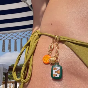Detailansicht von Bikini-Anhängern mit goldenen Muscheln und Fruchtanhängern für den Strand.