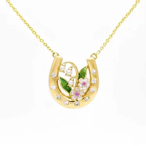 Macro view showing intricate floral enamel and crystal details on gold horseshoe pendant