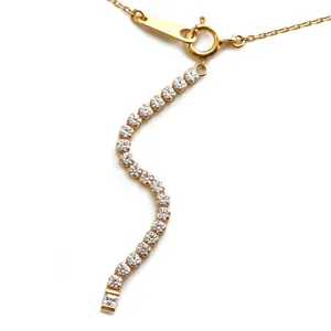 Dettaglio di una collana a nappa ondulata placcata in oro con cristalli tondi scintillanti.