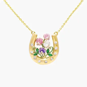 Close-up detail of a gold horseshoe necklace with colorful enamel flowers and crystals