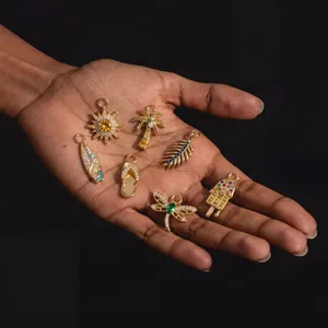 Vue détaillée de divers pendentifs dorés sertis de pierres colorées dans une main.