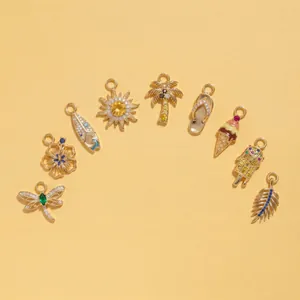 Vue détaillée de plusieurs pendentifs d'été dorés avec motifs soleil, palmier et libellule