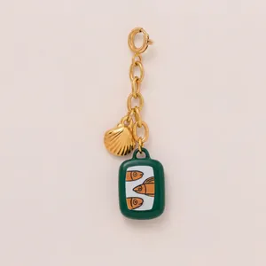 Detailansicht von Goldmuschel- und grünen Fisch-Emaille-Anhängern für Strandschmuck