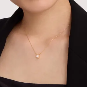 Primo piano di una collana placcata oro con ciondolo in zircone cubico quadrato al collo.