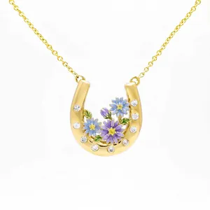 Detailed view of a gold-plated horseshoe necklace with enamel flowers and crystals