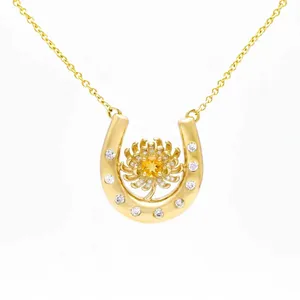 Detailed view of a gold horseshoe necklace with a yellow floral gemstone centerpiece.
