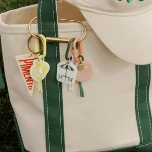 Close-up of colorful aesthetic acrylic bag pendants attached to a canvas tote bag strap.