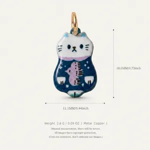 Macro view of cute enamel cat pendant with bird pattern and gold-tone copper finish