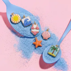 Kreative Makroaufnahme sommerlicher Emaille-Anhänger mit blauen Löffeln und Sand