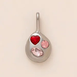 Vue détaillée d'un pendentif organique en acier avec cœur rouge et pierres roses