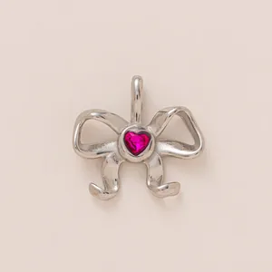 Détail d'un pendentif nœud en acier inoxydable argenté orné d'une pierre en cœur rose.