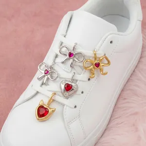 Gros plan détaillé de breloques de chaussures en forme de cœur et de nœud avec cristaux rouges