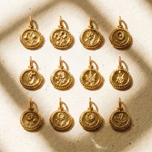 Detailed view of twelve vintage gold birth flower coin pendants on textured paper