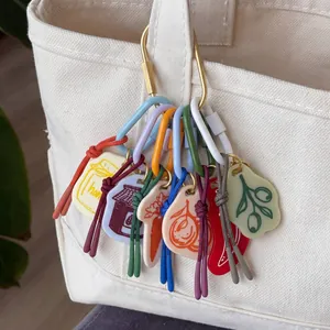 Detail view of colorful hand-drawn fruit and vegetable pendants on a canvas bag