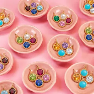 Detailed view of assorted birthstone coin pendants in gold plating on pink display