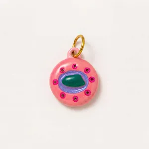 Gros plan d'un pendentif rond en émail rose avec centre vert et anneau doré brillant