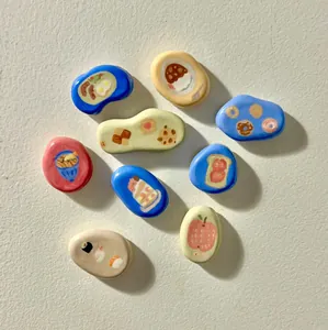 Group of colorful hand-painted food-themed pebble charms for DIY jewelry making.