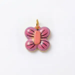 Vue détaillée d'un pendentif papillon en émail rose et acier inoxydable plaqué or.