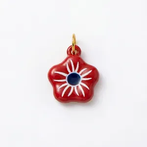 Gros plan d'un pendentif en forme de fleur rouge avec motif œil et anneau doré.