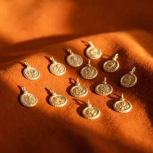 Detailed macro view of twelve vintage embossed gold flower pendants on orange fabric