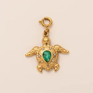Detail of a golden sea turtle charm with a pear-cut green gemstone and sparkling crystals